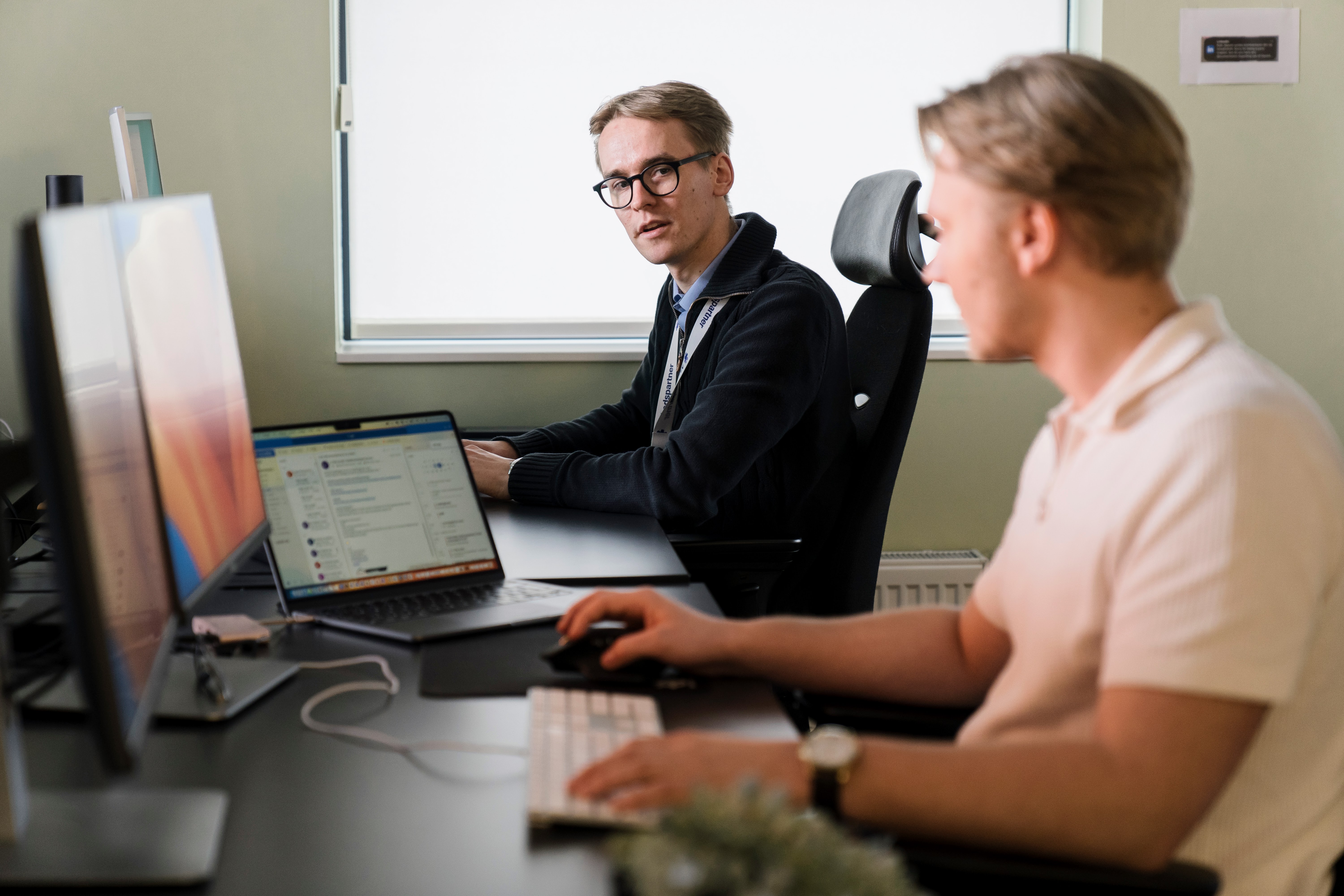 To ansatte som sitter ved siden av hverandre på kontoret og jobber på datamaskinen 