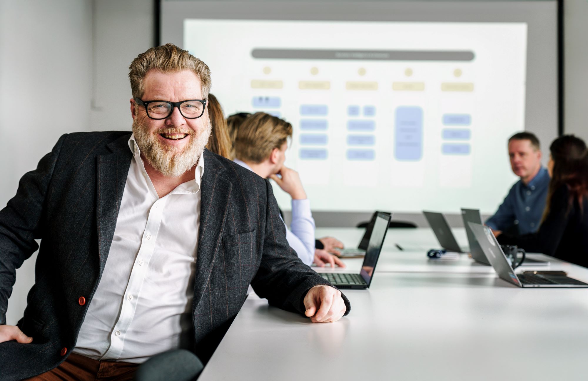 Mann som sitter ved et bord og smiler 